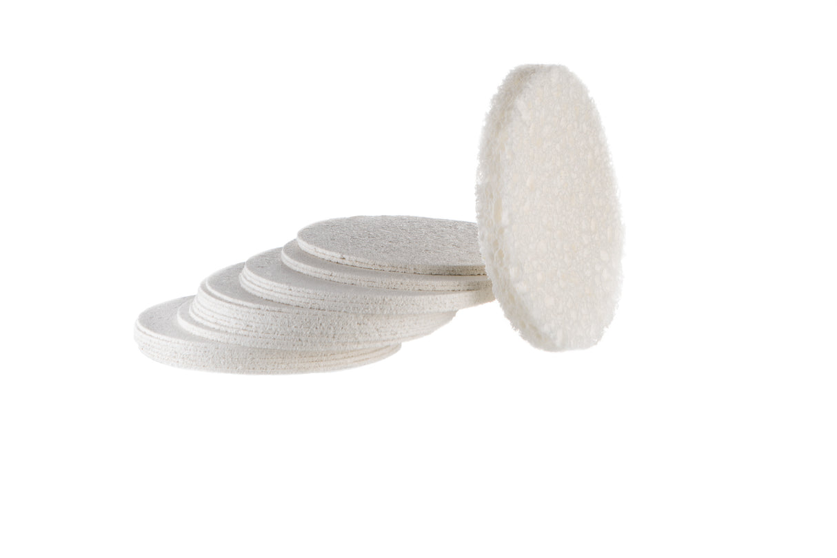 Compressed cellulose facial sponges stacked next to one expanded sponge showing before and after use on white background