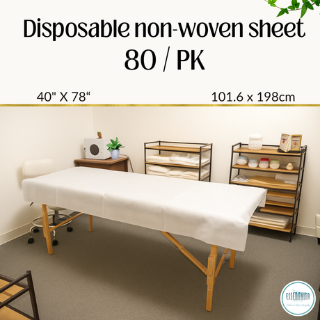 Disposable non-woven bed sheet fully covering massage bed in bright spa treatment room with towels and hot towel warmer