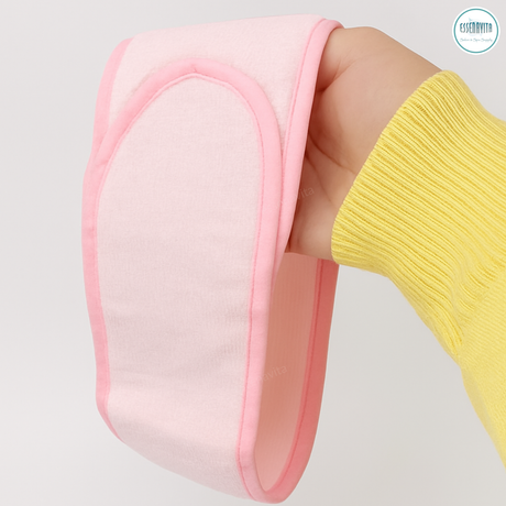 Single pink microfiber spa headband with adjustable wide Velcro held in hand on white background