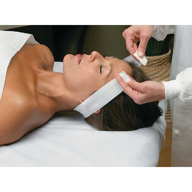 Professional esthetician performing a facial treatment using an Essenavita disposable stretch headband with Velcro closure.