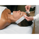 Professional esthetician performing a facial treatment using an Essenavita disposable stretch headband with Velcro closure.