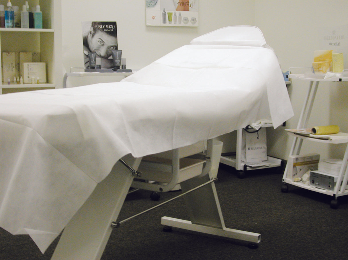 Non-woven disposable bed sheet placed on a spa treatment table in a clinic room