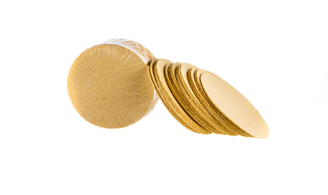 Yellow compressed cellulose facial sponges in shrink poly packaging with loose sponges on white background